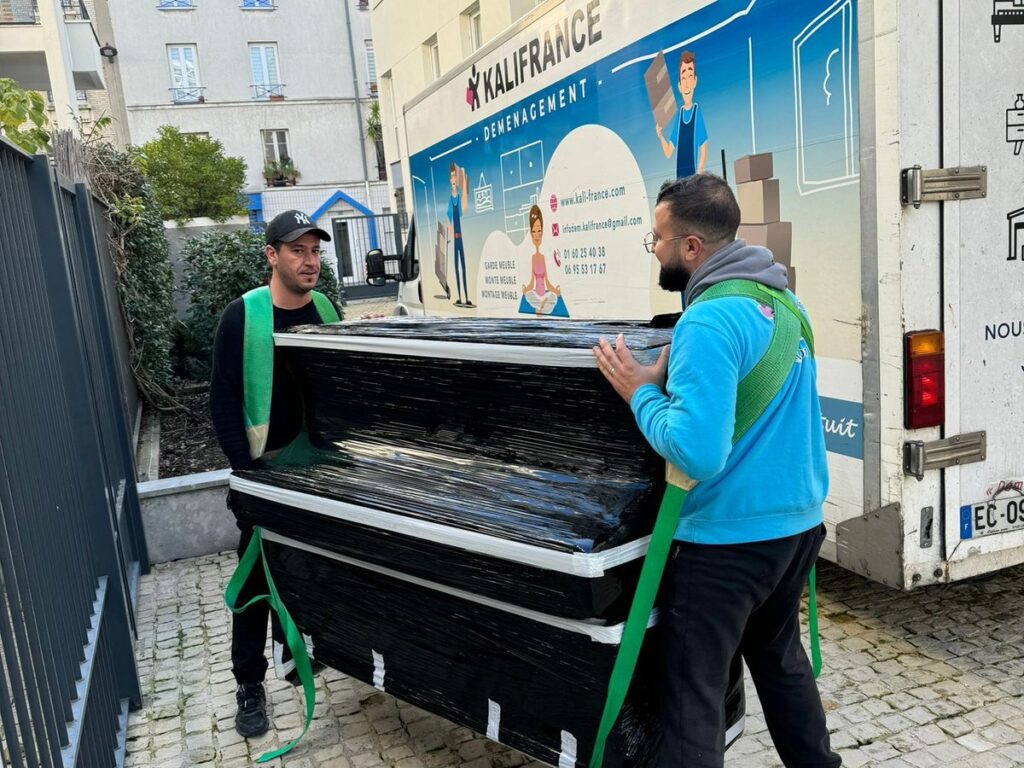 Déménageurs Kalifrance portant un meuble lourd protégé avec des sangles